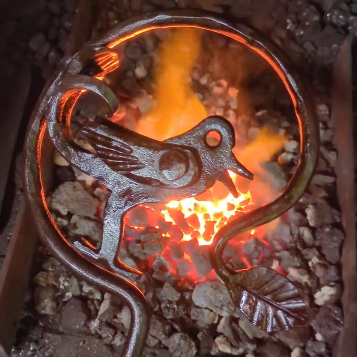 Geschmiedeter Vogel vor glühendem Feuer.